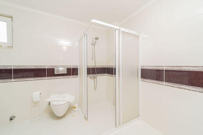 The light-colored tiles and the shower cabin contribute to the stylish ambiance of the bathroom.