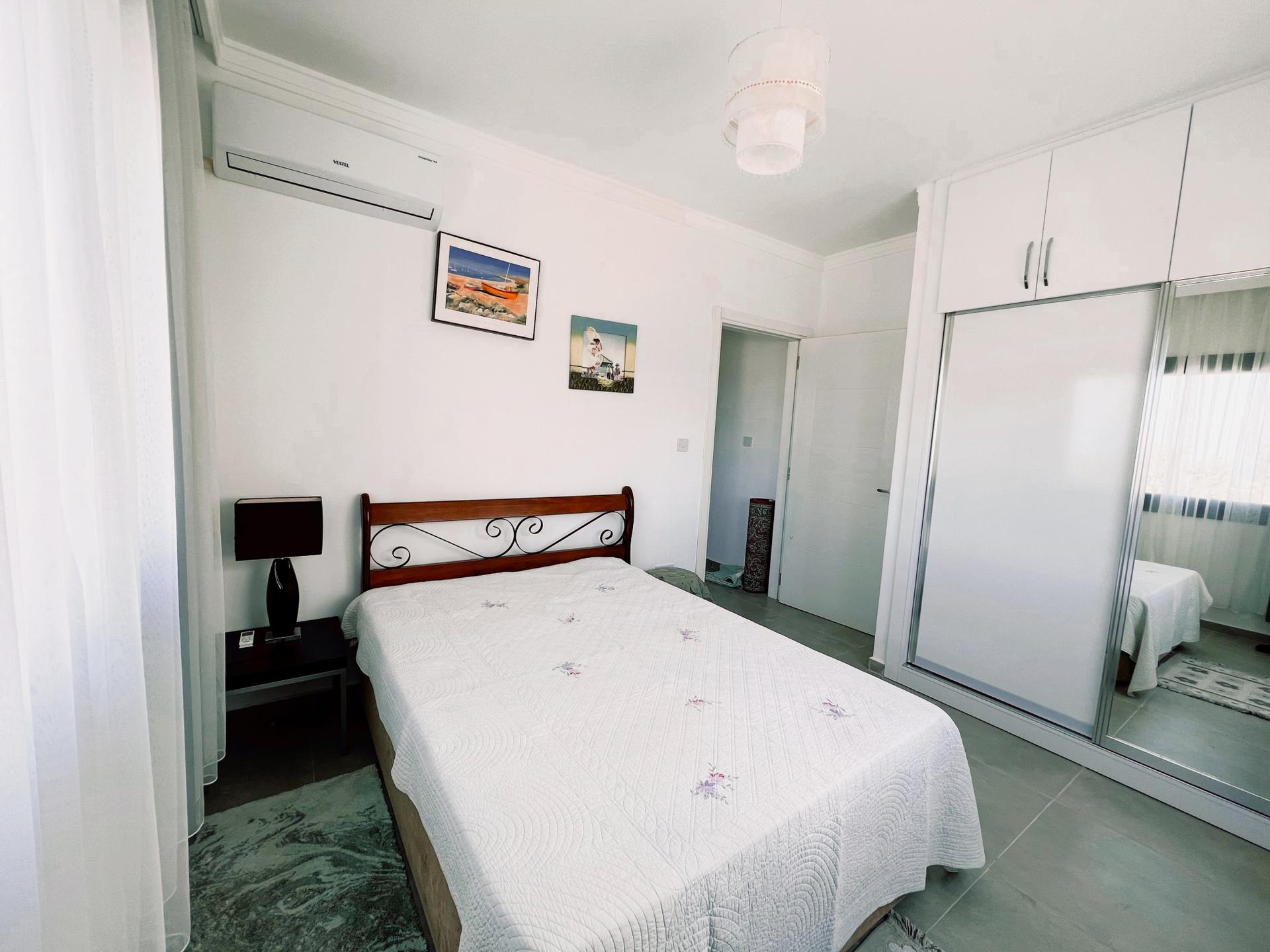 A sleeping sanctuary dominated by white with its AC, large wardrobe and comfortable double bed.