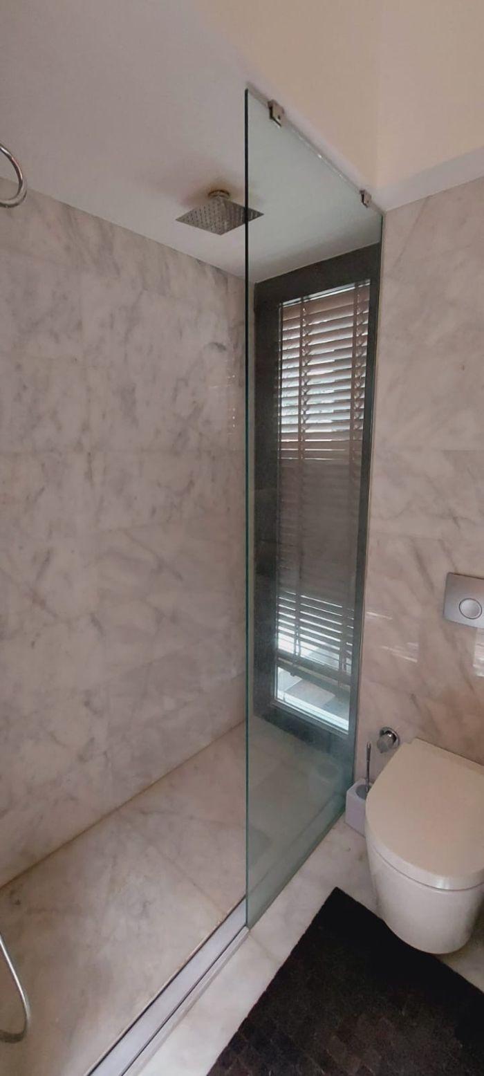 The light-colored tiles and the shower cabin contribute to the stylish ambiance of the bathroom.