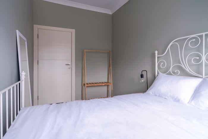 This bedroom also features a double bed, a dress hanger, and a full-length mirror for convenience.