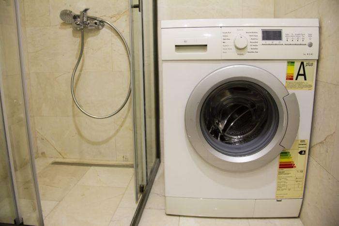 The washing machine can be found in the modern bathroom.