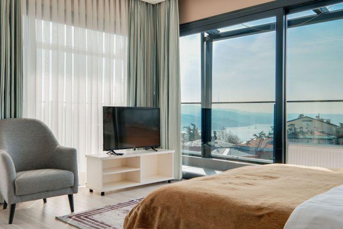 A cozy bedroom featuring panoramic views of the mesmerizing Bosphorus, blending comfort with breathtaking scenery.