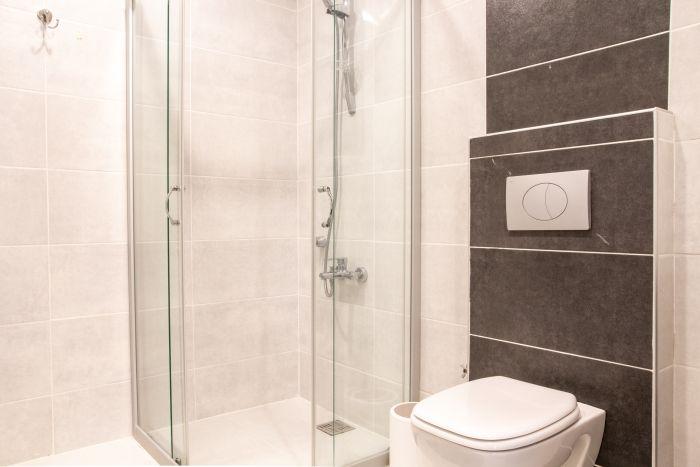 The modernly designed bathroom has a large shower cabin.